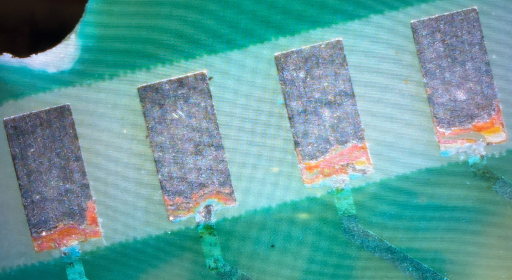 Zoomed in on four pads which have corroded away from the traces connected to them.